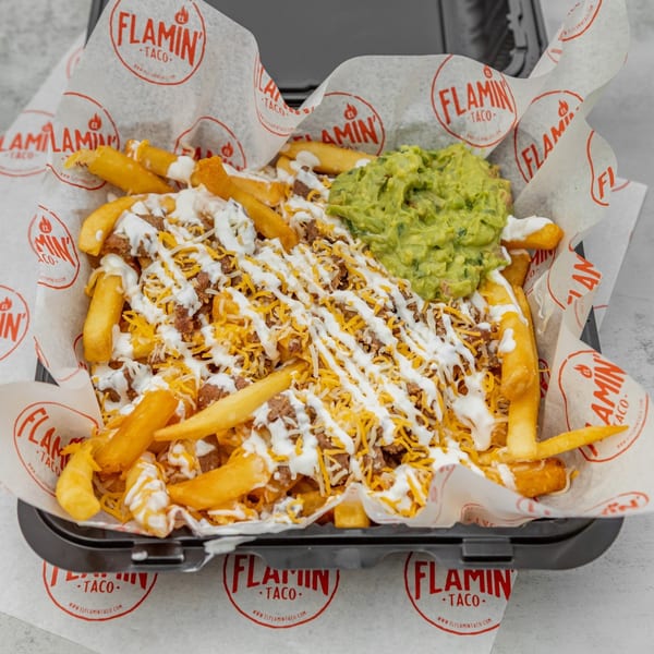 El Flamin Taco's carne asada fries, topped with cheese, sour cream, and a side of guacamole.