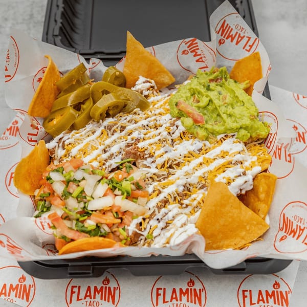 El Flamin Taco nachos with meat, cheese, sour cream, guacamole, pico de gallo, and jalapeños.