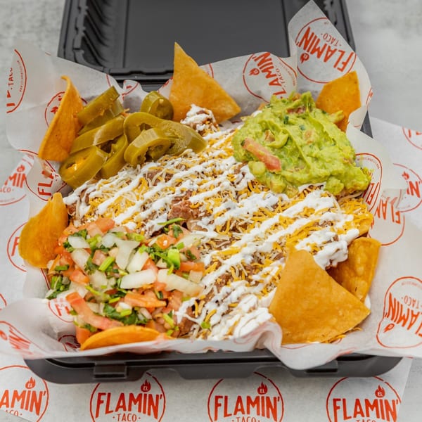 El Flamin Taco nachos with meat, cheese, sour cream, guacamole, pico de gallo, and jalapeños.