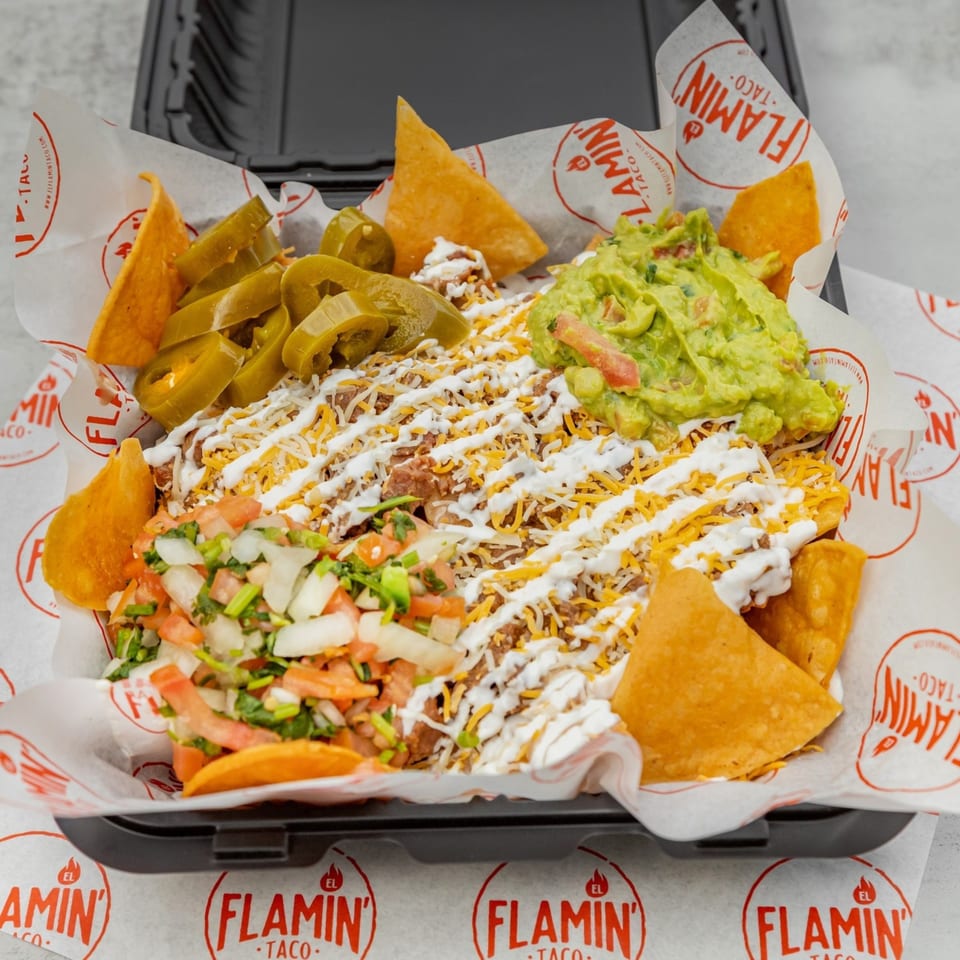 El Flamin Taco nachos with meat, cheese, sour cream, guacamole, pico de gallo, and jalapeños.