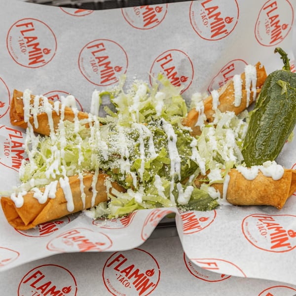 El Flamin Taco's taquitos with lettuce, cheese, crema, and a large green pepper.